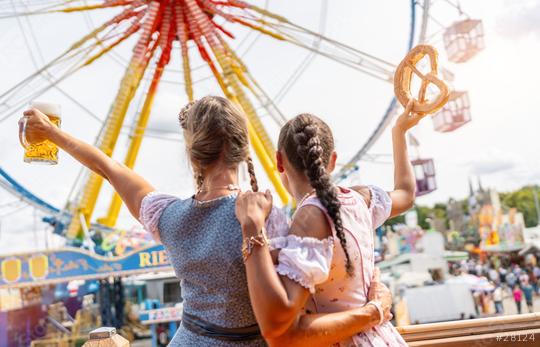 bavarian women in tracht holding a beer mug and pretzel aloft at a lively fairground with Ferris wheel at oktoberfest or duld in germany  : Stock Photo or Stock Video Download rcfotostock photos, images and assets rcfotostock | RC Photo Stock.: