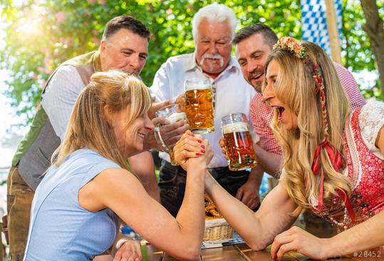 Bavarian women practicing the high art of arm wrestling with friends that cheer on in a beer garden or oktoberfest  : Stock Photo or Stock Video Download rcfotostock photos, images and assets rcfotostock | RC Photo Stock.: