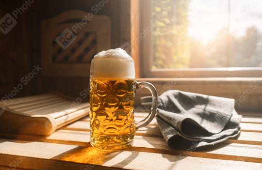 Beer mug with frothy beer rest on a ledge in a sauna, catching sunlight. Nearby finnish Sauna hats on a wooden bench. spa and wellness concept image  : Stock Photo or Stock Video Download rcfotostock photos, images and assets rcfotostock | RC Photo Stock.: