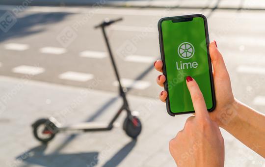 BERLIN, GERMANY AUGUST 2019: Woman hand holding iphone Xs with logo of LIME app displayed on a smartphone to rent a e-Scooter. Lime is a rental electric scooter company. Quick and easy way to travel  : Stock Photo or Stock Video Download rcfotostock photos, images and assets rcfotostock | RC Photo Stock.: