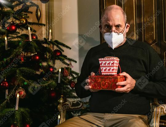 Caucasian Senior man wearing covid-19 mask sitting on chair alone holding a gift in Christmas decorated room . Coronavirus self isolation and celebrate Christmas alone concept  : Stock Photo or Stock Video Download rcfotostock photos, images and assets rcfotostock | RC Photo Stock.: