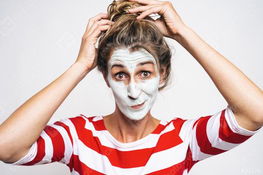 Cheerful woman correcting hair bun, has clay mask on face, enjoys softness, has beauty treatments at home, on gray background. Skin care concept image  : Stock Photo or Stock Video Download rcfotostock photos, images and assets rcfotostock | RC Photo Stock.: