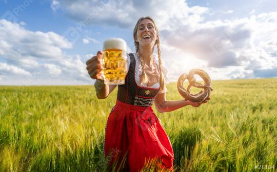 Cheerful woman in traditional Bavarian attire holding a beer and pretzel in a field ready for Oktoberfest or dult festival in munich.    : Stock Photo or Stock Video Download rcfotostock photos, images and assets rcfotostock | RC Photo Stock.: