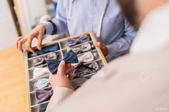 Client choosing a bow tie from a collection in a tailor