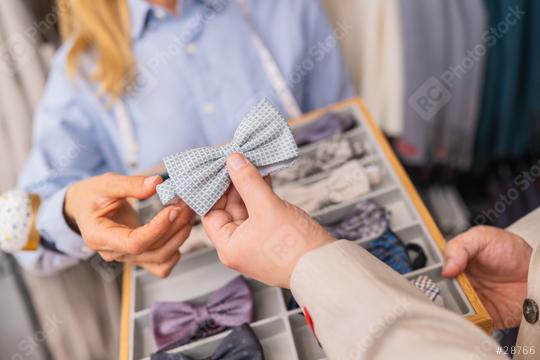 Client holding a light blue patterned bow tie, with tailor