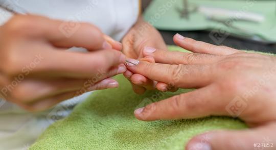 Close-up of a manicure with a pusher removes calluses from a client