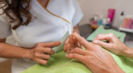 Close-up of a manicurist buffing a client