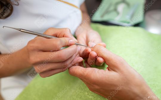 Close-up of a manicurist using a cuticle pusher on a client