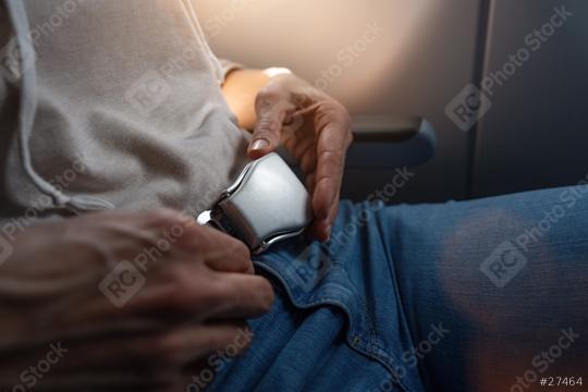 Close-up of a passenger securing a seat belt on an airplane, with a hand on buckle. safe flight on airplane concept image  : Stock Photo or Stock Video Download rcfotostock photos, images and assets rcfotostock | RC Photo Stock.: