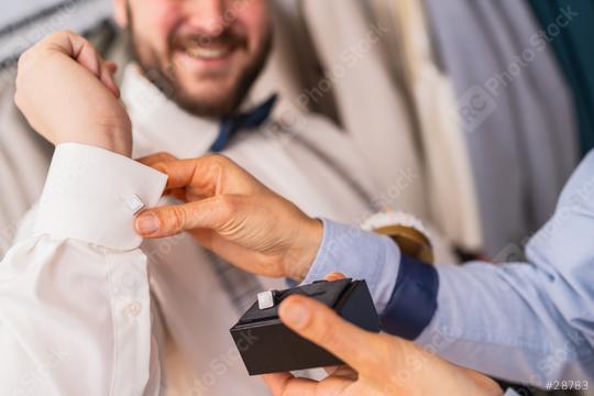 Close-up of a tailor fitting cufflinks on a client