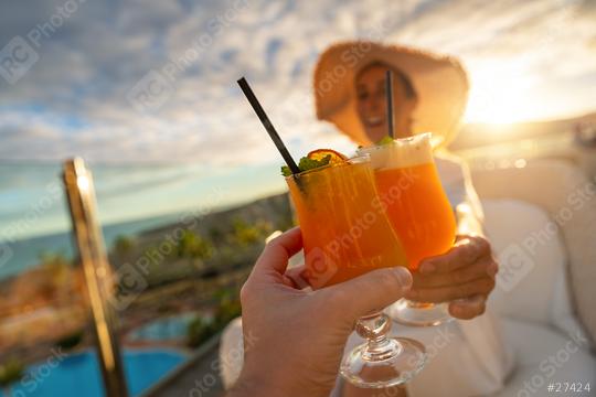 Close-up of a tropical cocktail with a straw held by a woman in a sun hat at tropical beach hotel on sunset  : Stock Photo or Stock Video Download rcfotostock photos, images and assets rcfotostock | RC Photo Stock.: