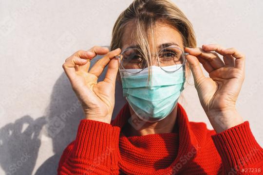 close-up of a woman looks at camera adjusting her round glasses, wearing a turquoise face mask and a red sweater. Corona pandemic safty concept image  : Stock Photo or Stock Video Download rcfotostock photos, images and assets rcfotostock | RC Photo Stock.: