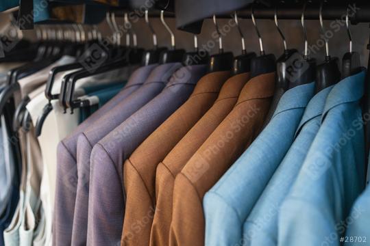 Close-up of assorted suits on hangers, focused on texture and colors at a men