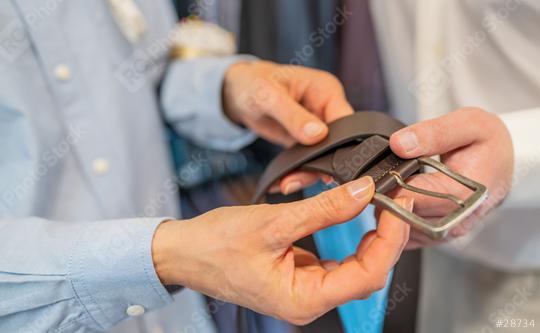 Close-up of hands holding a black leather belt with a silver buckle in a wedding store  : Stock Photo or Stock Video Download rcfotostock photos, images and assets rcfotostock | RC Photo Stock.: