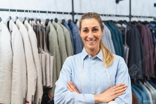 Confident tailor with arms crossed standing in front of suit jackets on hangers  : Stock Photo or Stock Video Download rcfotostock photos, images and assets rcfotostock | RC Photo Stock.: