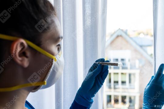 corona COVID-19 infection person looks at the clinical thermometer in quarantine - stay at home   : Stock Photo or Stock Video Download rcfotostock photos, images and assets rcfotostock | RC Photo Stock.: