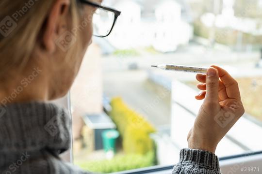 corona COVID-19 infection woman looks at the clinical thermometer in quarantine - stay at home  : Stock Photo or Stock Video Download rcfotostock photos, images and assets rcfotostock | RC Photo Stock.:
