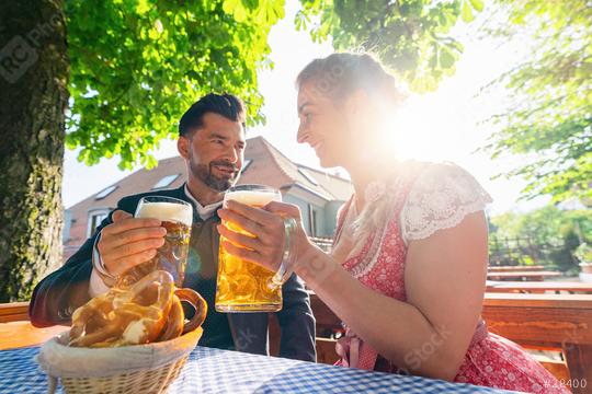 Couple in Bavarian Tracht sitting in Beer garden or oktoberfest and enjoying a glass of beer and the sun  : Stock Photo or Stock Video Download rcfotostock photos, images and assets rcfotostock | RC Photo Stock.: