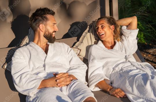 Couple in white robes reclining and enjoying a laugh on a lounger in the sunlight at a spa hotel   : Stock Photo or Stock Video Download rcfotostock photos, images and assets rcfotostock | RC Photo Stock.: