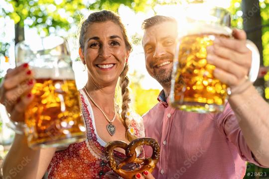 Couple looking and smiling at camera say cheers or clinking glasses with mug of beer in Bavarian beer garden or oktoberfest  : Stock Photo or Stock Video Download rcfotostock photos, images and assets rcfotostock | RC Photo Stock.: