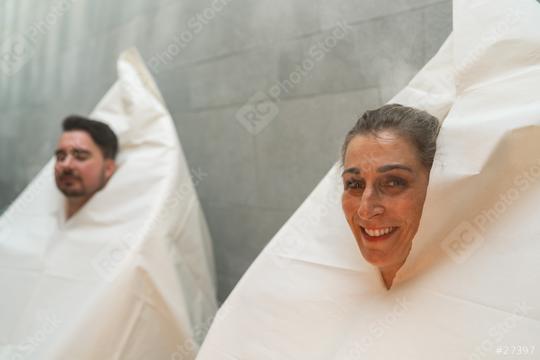 Couple wrapped in thermal spa steam sauna bags, woman smiling at camera, man relaxed in background at spa resort  : Stock Photo or Stock Video Download rcfotostock photos, images and assets rcfotostock | RC Photo Stock.: