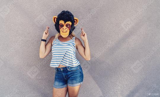 Crazy young woman with monkey mask stands on a gray wall and and cross fingers. copyspace for your individual text.   : Stock Photo or Stock Video Download rcfotostock photos, images and assets rcfotostock | RC Photo Stock.: