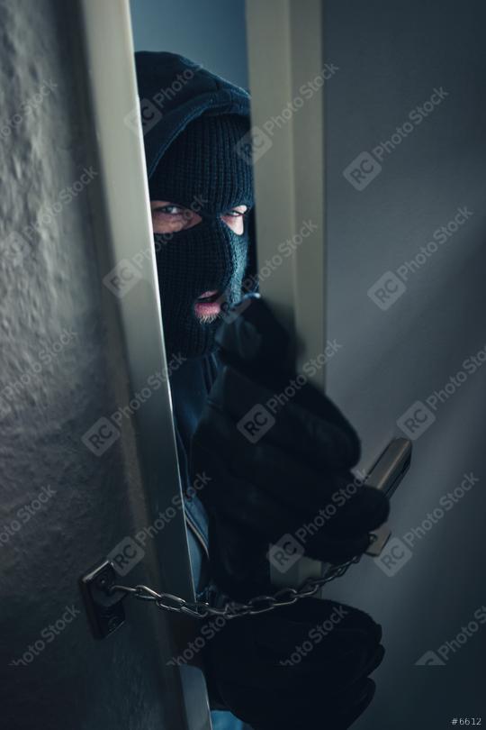 dangerous masked burglar breaking into a victim