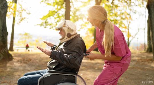 Elderly man in astronaut helmet and nurse in pink uniform laugh joyfully, with the man gesturing expansively in a park. Dementia retirement home concept image  : Stock Photo or Stock Video Download rcfotostock photos, images and assets rcfotostock | RC Photo Stock.: