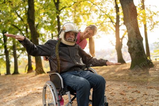 Elderly man in astronaut helmet joyfully extends arms wide, nurse beside him laughing, both in an autumn park. Dementia retirement home concept image  : Stock Photo or Stock Video Download rcfotostock photos, images and assets rcfotostock | RC Photo Stock.: