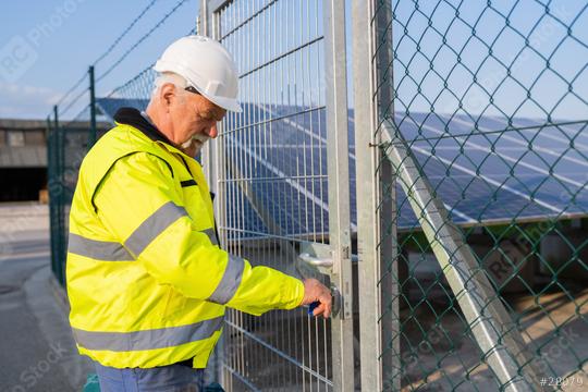 Electrical engineer in safety gear opening a gate to a solar field  : Stock Photo or Stock Video Download rcfotostock photos, images and assets rcfotostock | RC Photo Stock.: