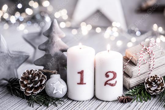 Elegant Christmas arrangement with two numbered candles, pinecones, fir branches, a small ornament, and wrapped gifts, set on a wooden surface with soft fairy lights in the background  : Stock Photo or Stock Video Download rcfotostock photos, images and assets rcfotostock | RC Photo Stock.: