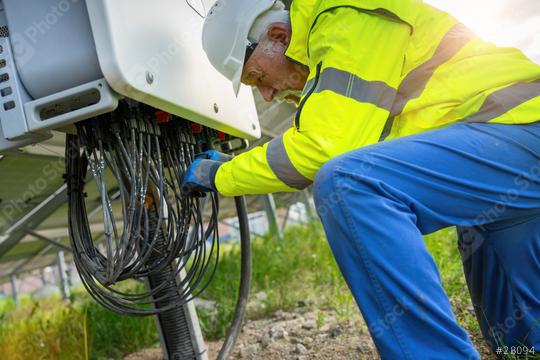 Engineer at a distribution station in a solar panel park handling cables. Alternative energy ecological concept image.  : Stock Photo or Stock Video Download rcfotostock photos, images and assets rcfotostock | RC Photo Stock.: