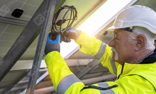 Engineer managing cables behind solar panels at a solar farm. Alternative energy ecological concept image.  : Stock Photo or Stock Video Download rcfotostock photos, images and assets rcfotostock | RC Photo Stock.: