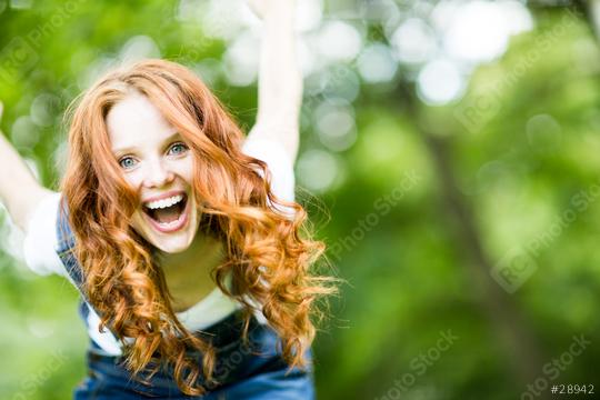 Excited red-haired woman with a big smile outdoors, enjoying a vibrant day in nature with a blurred green background, radiating happiness, energy, and carefree joy in a sunny environment  : Stock Photo or Stock Video Download rcfotostock photos, images and assets rcfotostock | RC Photo Stock.: