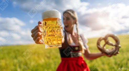 Exuberant woman in Bavarian dress holding a beer mug and pretzel in a sunny wheat field celebrating Oktoberfest festival in munich, germany  : Stock Photo or Stock Video Download rcfotostock photos, images and assets rcfotostock | RC Photo Stock.: