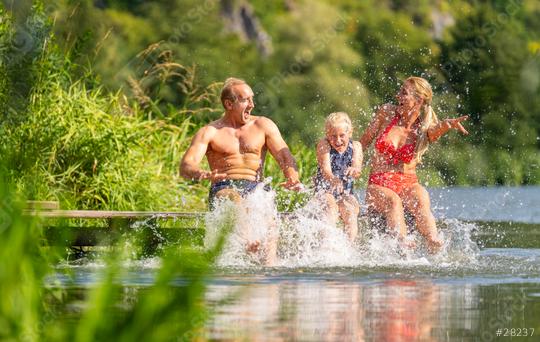 Family bathing and laughing while splashing her feets in the water on a wooden dock surrounded by greenery at a river in germany  : Stock Photo or Stock Video Download rcfotostock photos, images and assets rcfotostock | RC Photo Stock.: