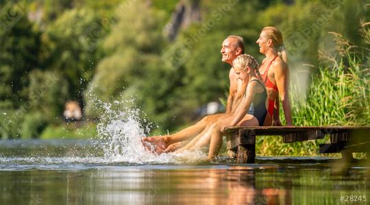 family joyfully splashes water while sitting on a wooden dock at a lake during summer   : Stock Photo or Stock Video Download rcfotostock photos, images and assets rcfotostock | RC Photo Stock.: