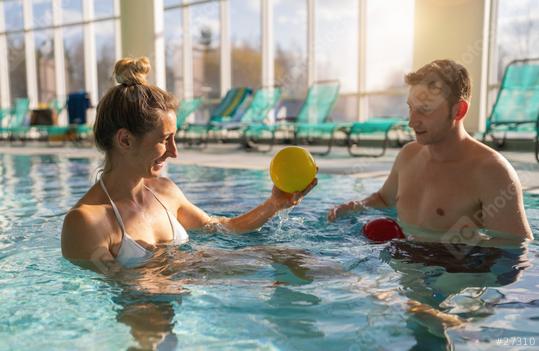 Female client and male trainer smiling and using colorful exercise balls in a sunny indoor pool  : Stock Photo or Stock Video Download rcfotostock photos, images and assets rcfotostock | RC Photo Stock.: