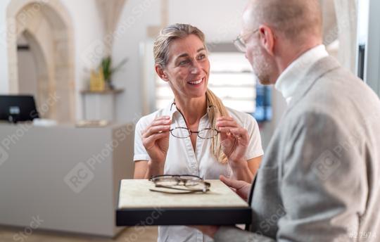 Female customer trying on new glasses with optician holding a tray of eyewear in an optical store  : Stock Photo or Stock Video Download rcfotostock photos, images and assets rcfotostock | RC Photo Stock.: