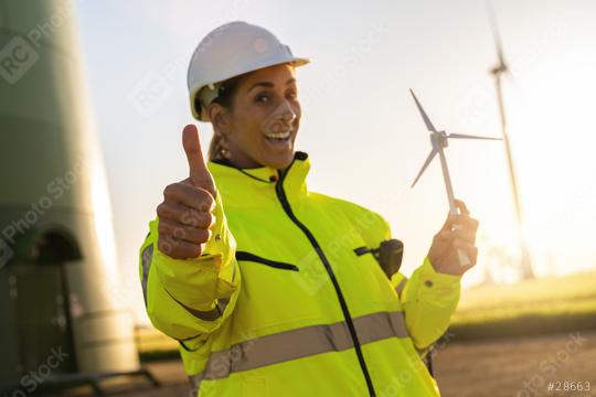 female engineer holding wind turbine model and thumbs up at a windfarm. New Energy concept image  : Stock Photo or Stock Video Download rcfotostock photos, images and assets rcfotostock | RC Photo Stock.: