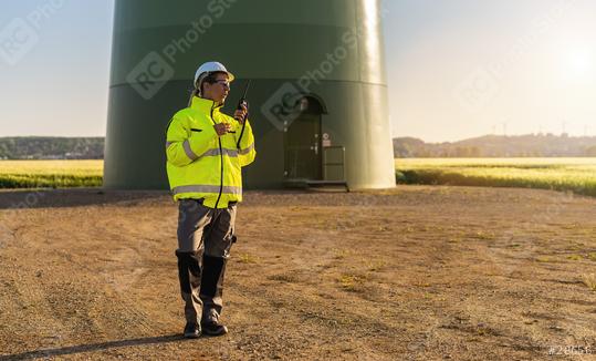 female engineer with safety jacket standing in front of a wind turbine using walkie talkie to checking wind turbine system at a new energy farm  : Stock Photo or Stock Video Download rcfotostock photos, images and assets rcfotostock | RC Photo Stock.: