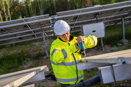 Female technician using a cordless drill on solar panel structure in a field. Alternative energy ecological concept image.  : Stock Photo or Stock Video Download rcfotostock photos, images and assets rcfotostock | RC Photo Stock.: