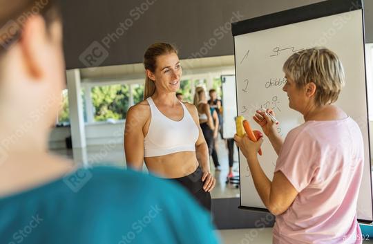 Fitness class with a woman writing on a whiteboard about nutritional advice holding a banana, apple and a carrot, focusing on nutrition  : Stock Photo or Stock Video Download rcfotostock photos, images and assets rcfotostock | RC Photo Stock.: