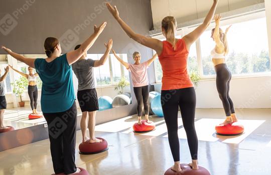 Fitness group balancing on Bosu Balls with raised arms in a bright studio  : Stock Photo or Stock Video Download rcfotostock photos, images and assets rcfotostock | RC Photo Stock.: