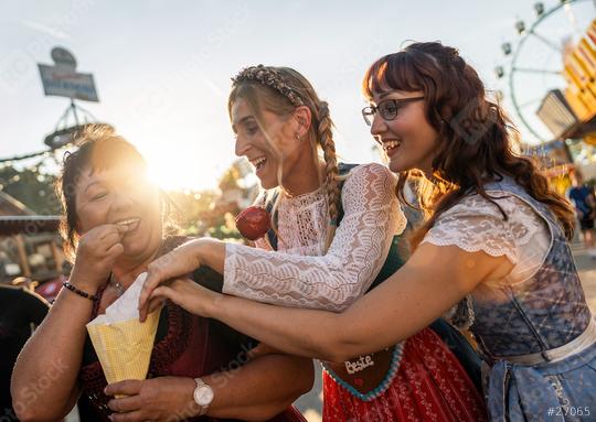 Friends eat roasted almonds together from the paper bag in front of the gingerbread stand at a Bavarian fair or oktoberfest or duld in national costume or Dirndl  : Stock Photo or Stock Video Download rcfotostock photos, images and assets rcfotostock | RC Photo Stock.:
