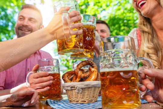 friends in Tracht, Dirndl and Lederhosen having fun sitting on table drinking beer and eating pretzels in Beer garden or oktoberfest in Bavaria, Germany  : Stock Photo or Stock Video Download rcfotostock photos, images and assets rcfotostock | RC Photo Stock.: