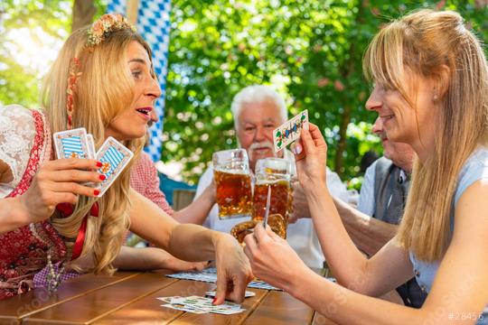 Friends in traditional costume playing traditional card game of Schafkopf in a German beer garden or oktoberfest  : Stock Photo or Stock Video Download rcfotostock photos, images and assets rcfotostock | RC Photo Stock.: