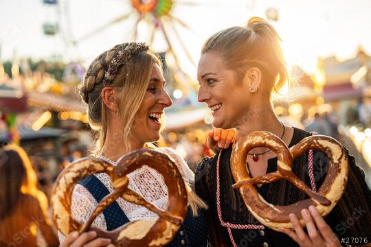 girlfriends look at each other  holding pretzel or brezen on a Bavarian fair or oktoberfest or duld in national costume or Dirndl in germany   : Stock Photo or Stock Video Download rcfotostock photos, images and assets rcfotostock | RC Photo Stock.: