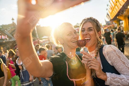 Girlfriends making selfie wearing dirndl and holding candy apples at a Bavarian fair or oktoberfest or duld in national costume or Dirndl  : Stock Photo or Stock Video Download rcfotostock photos, images and assets rcfotostock | RC Photo Stock.: