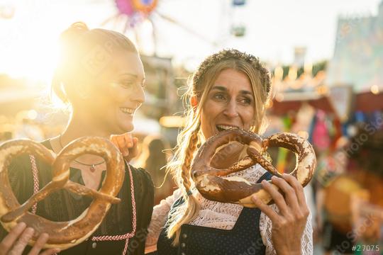 Girlfriends together on a Bavarian fair or oktoberfest or duld in national costume or Dirndl eating pretzel or brezen  : Stock Photo or Stock Video Download rcfotostock photos, images and assets rcfotostock | RC Photo Stock.: